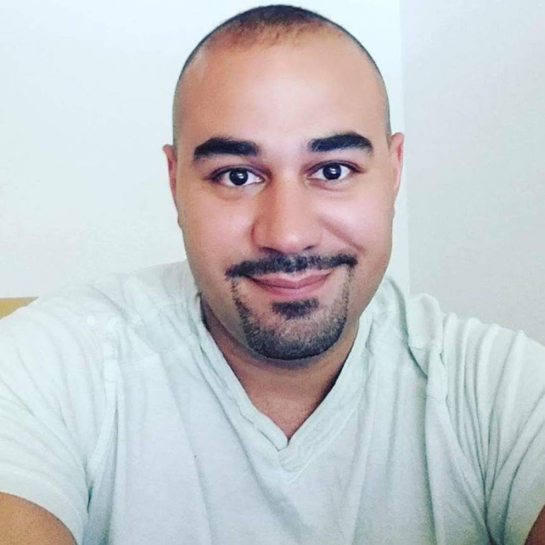 Close-up portrait of Cristopher Cristia smiling with a light green shirt.